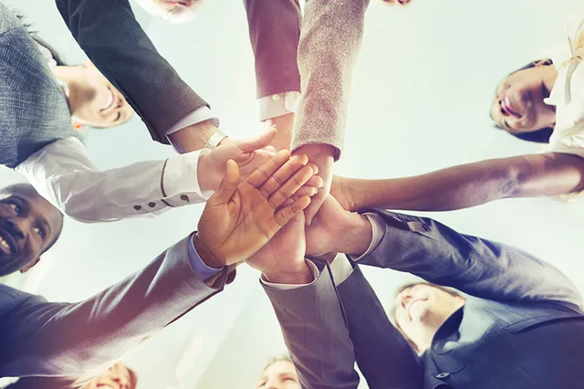 A diverse team putting their hands together
